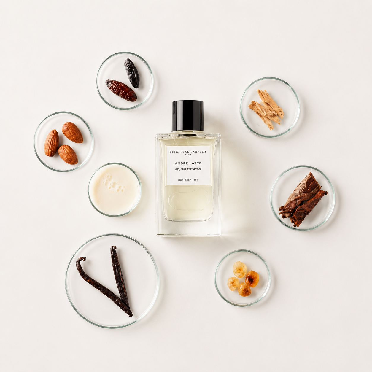Ambre Latte d'Essential Parfums, eau de parfum 100 ml entourée de vanille, amandes, lait, benjoin, bois de santal et cannelle sur fond clair.