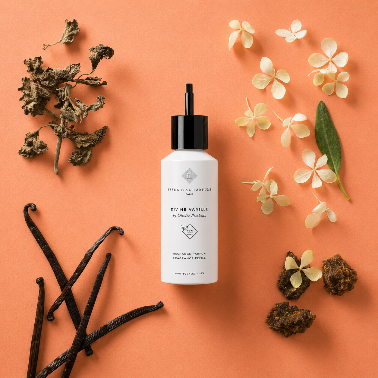 Recharge parfum Divine Vanille 150 ml Essential Parfums entourée de gousses de vanille, fleurs blanches et feuilles séchées sur fond pêche.
