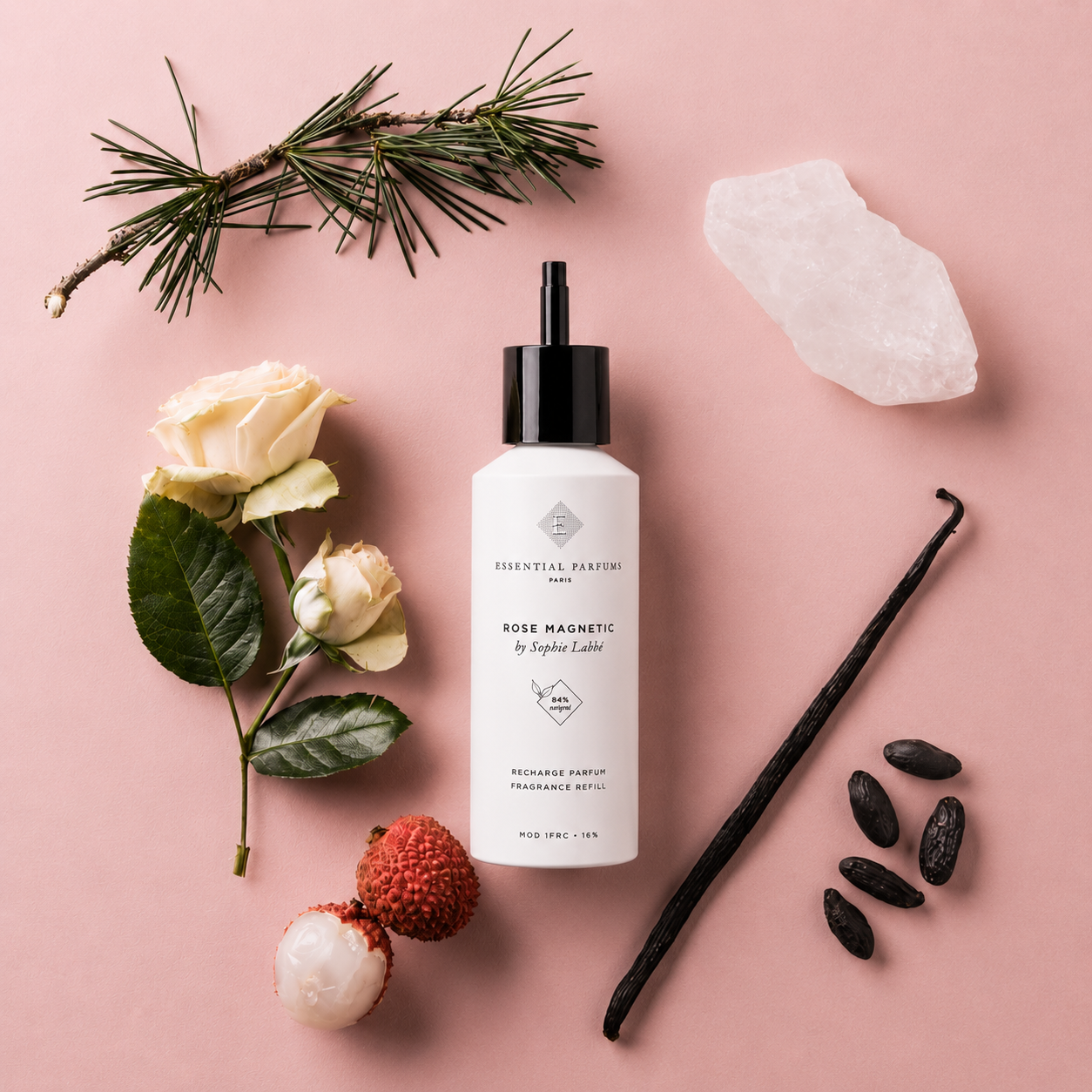Recharge parfum Rose Magnetic 150 ml Essential Parfums entourée de rose blanche, litchi, vanille, cristal et branche de pin sur fond rose.