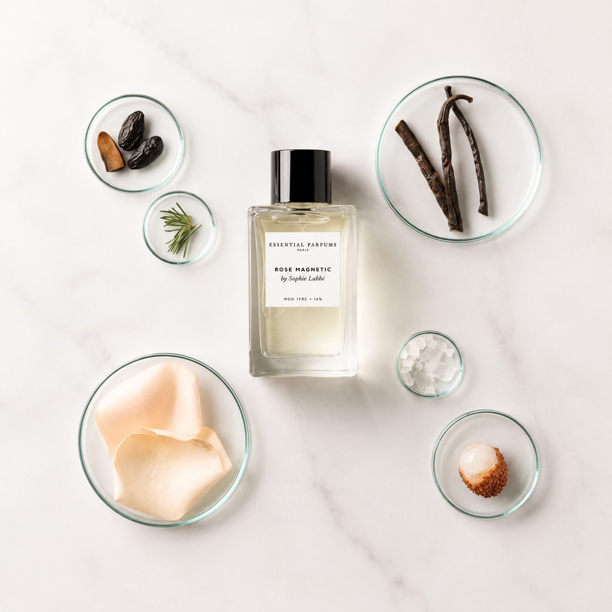 Rose Magnetic d'Essential Parfums, eau de parfum 100 ml entourée de pétales de rose, vanille, litchi, romarin et fèves tonka sur fond clair.