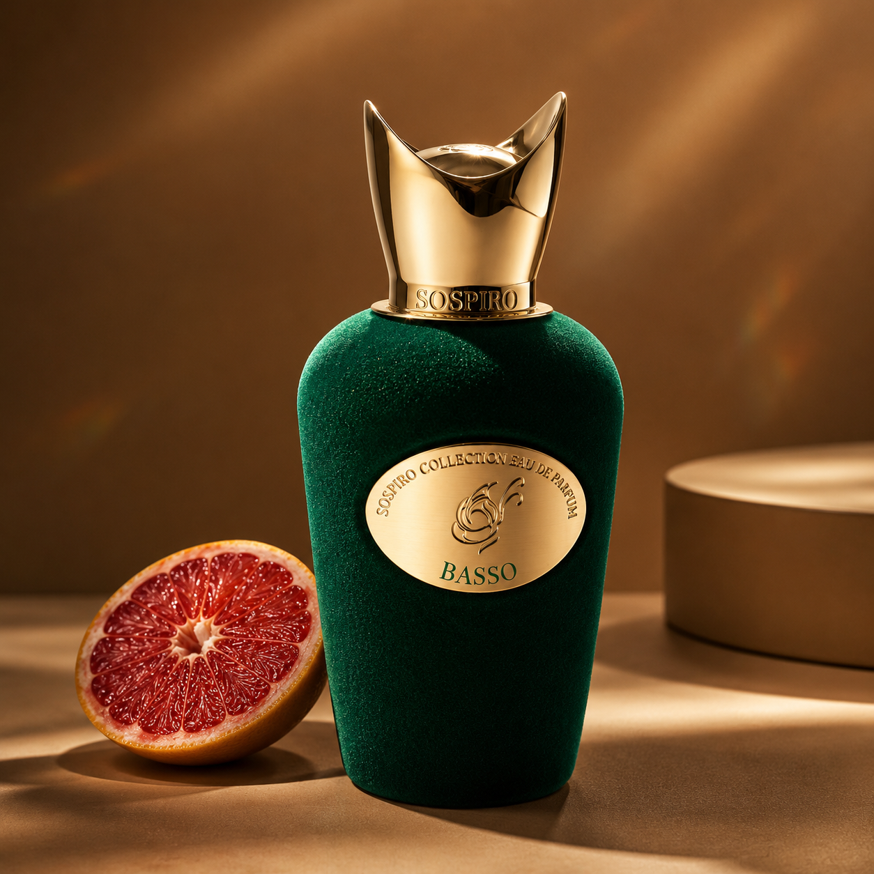 Basso de Sospiro, eau de parfum 100 ml, flacon en mise en scène avec un demi-pamplemousse sur fond ocre.
