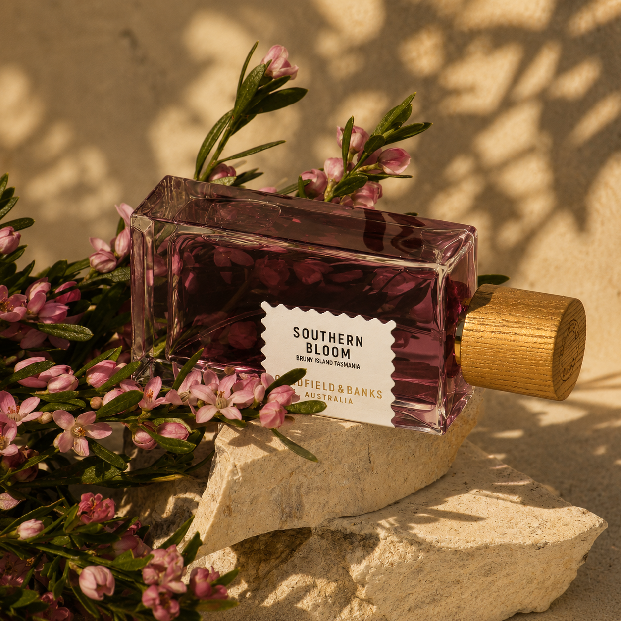 Parfum Southern Bloom Goldfield & Banks Australia en mise en scène florale avec fleurs roses et pierres naturelles