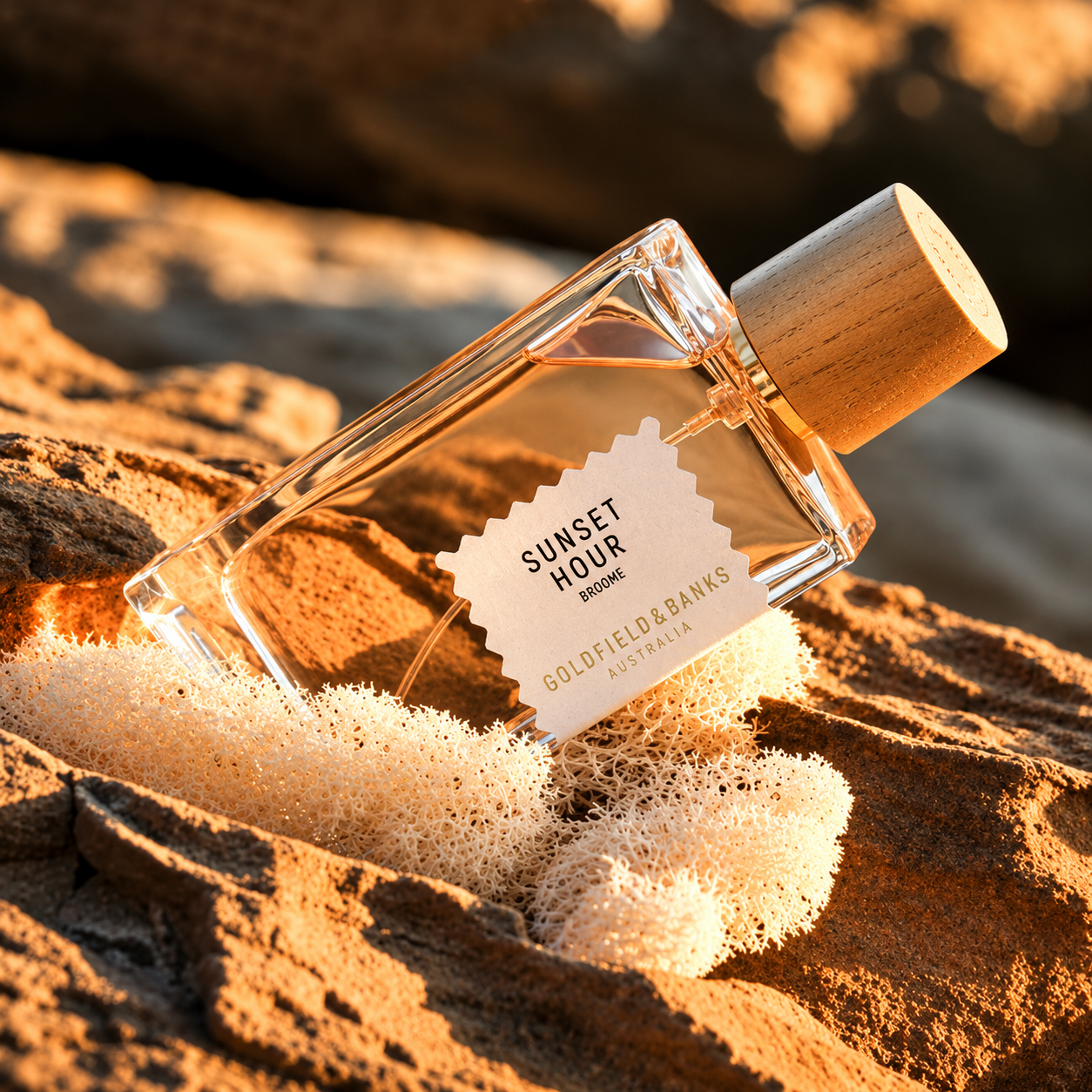 Parfum Sunset Hour Goldfield & Banks Australia en mise en scène sur rochers avec lumière dorée de coucher de soleil