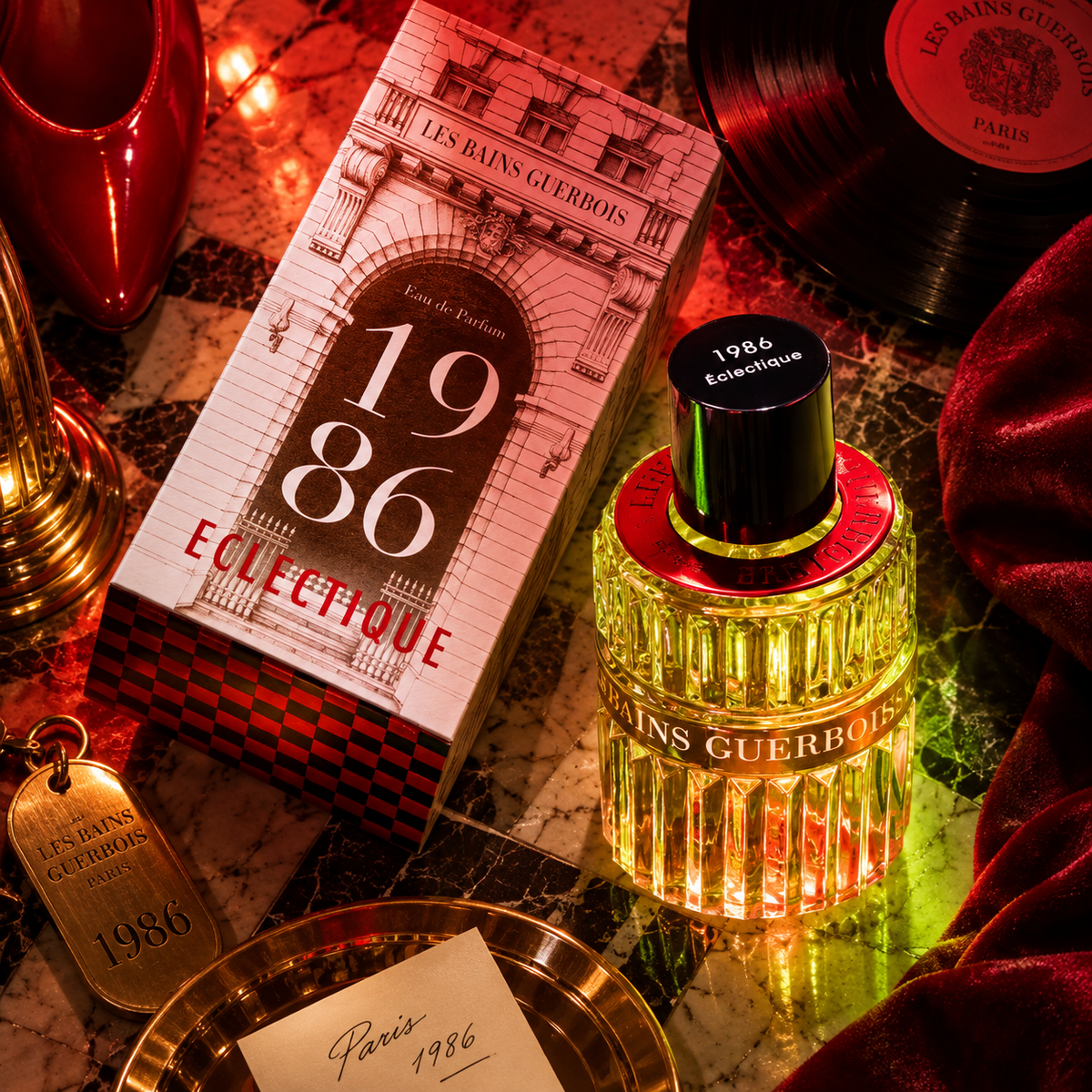 1986 Éclectique de Les Bains Guerbois, eau de parfum 100 ml, flacon et étui sur un marbre rouge, entre disque vinyle et velours.