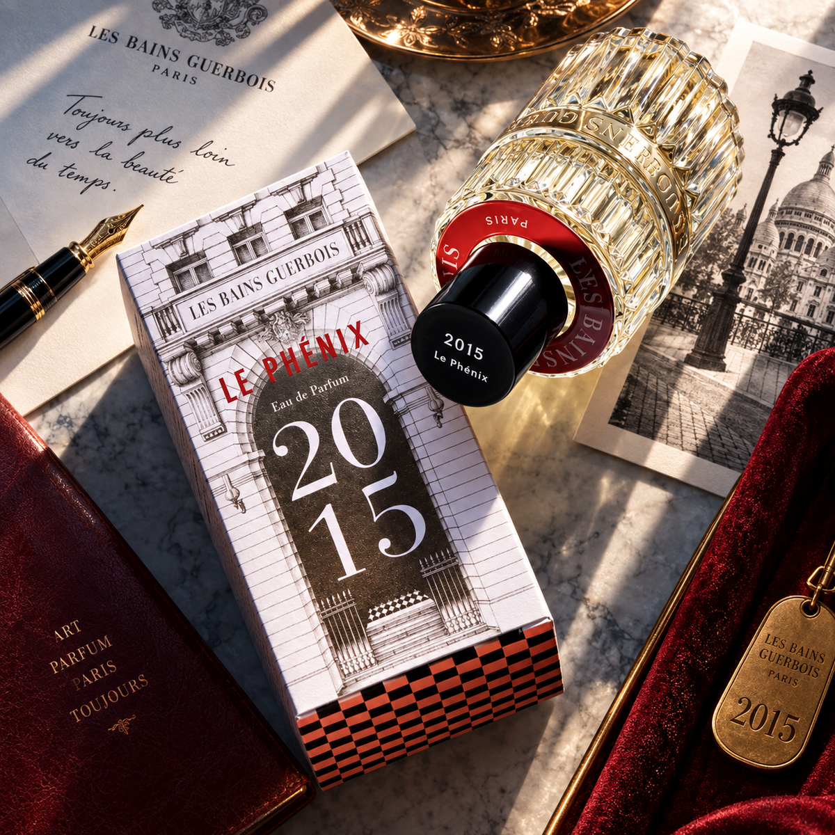 2015 Le Phénix de Les Bains Guerbois, eau de parfum 100 ml, flacon et étui sur un marbre clair, entre stylo plume et écrin de velours rouge.