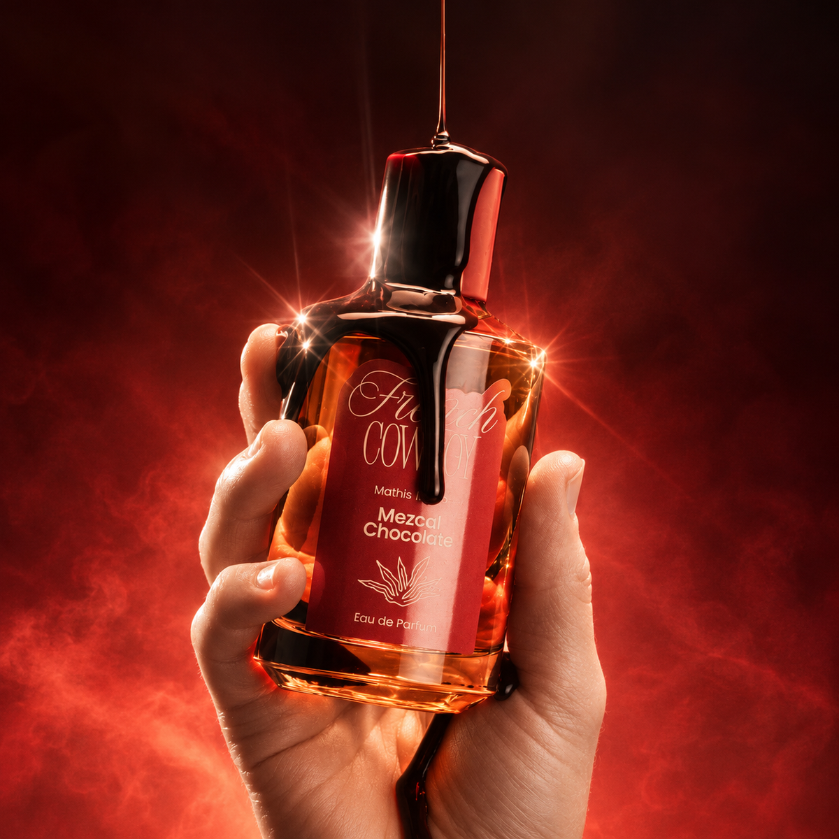 Mezcal Chocolat de French Cowboy, eau de parfum 100 ml, flacon tenu en main et nappé de chocolat sur fond rouge.