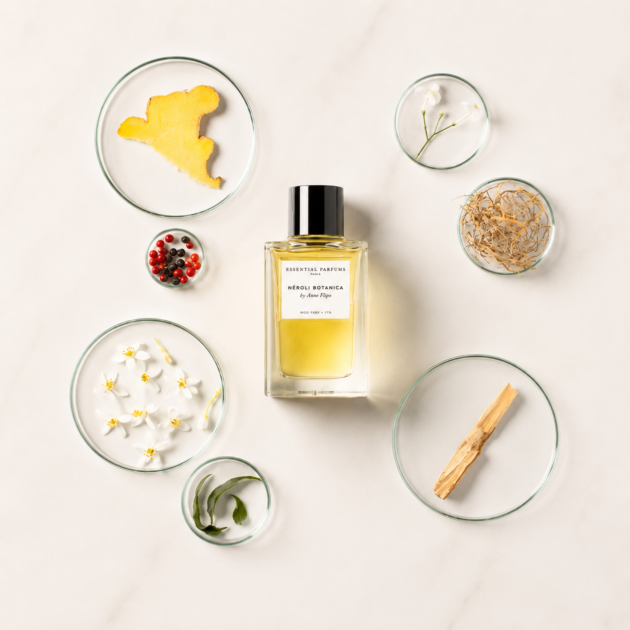 Néroli Botanica d'Essential Parfums, eau de parfum 100 ml entourée de fleur d'oranger, néroli, gingembre, poivre rose, vétiver et bois de santal sur fond clair.