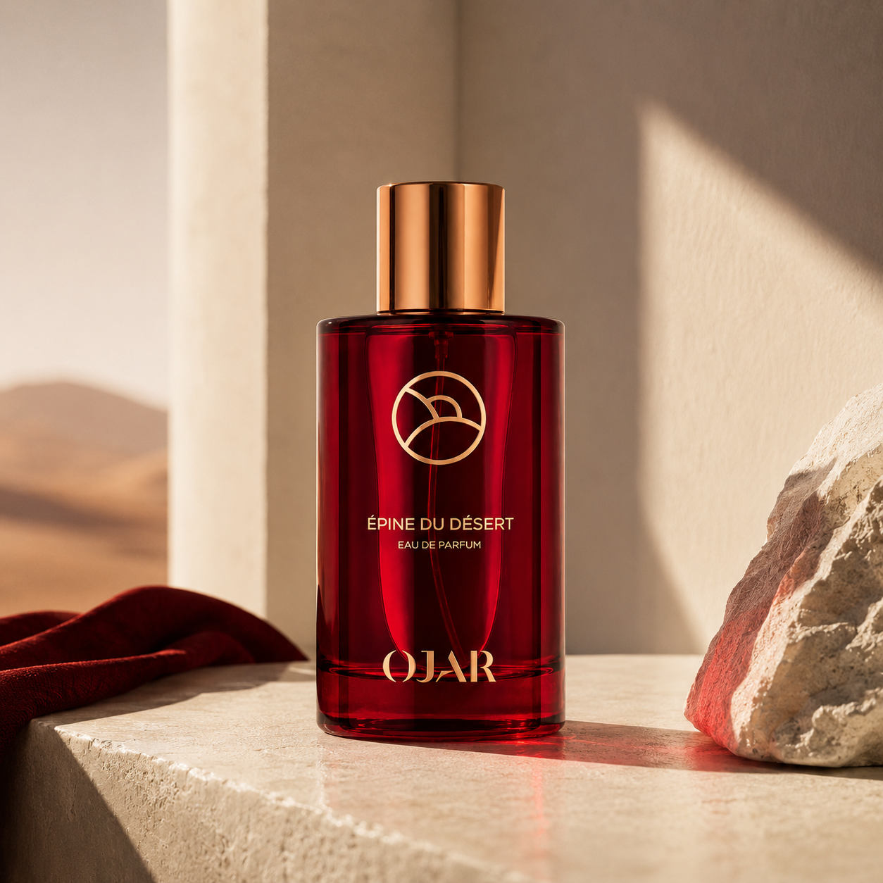 Épine du Désert d'OJAR, eau de parfum, flacon en mise en scène désertique avec roche naturelle et drapé rouge.