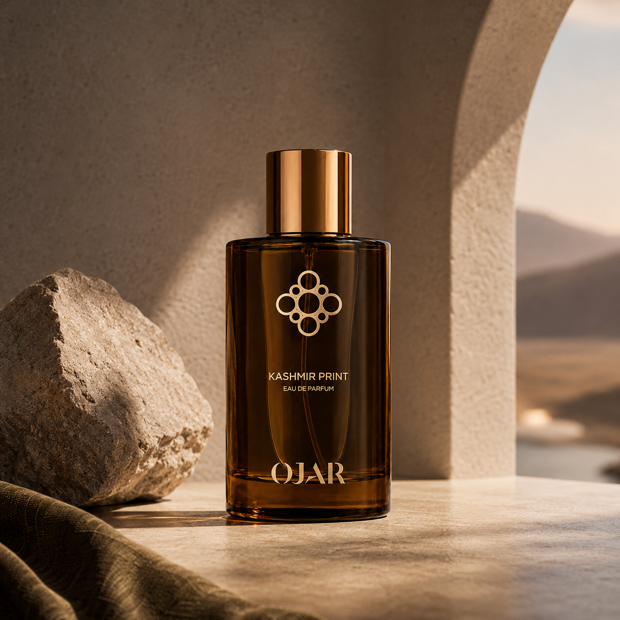 Kashmir Print d'OJAR, eau de parfum, flacon en mise en scène dans un décor minéral avec arche en pierre.
