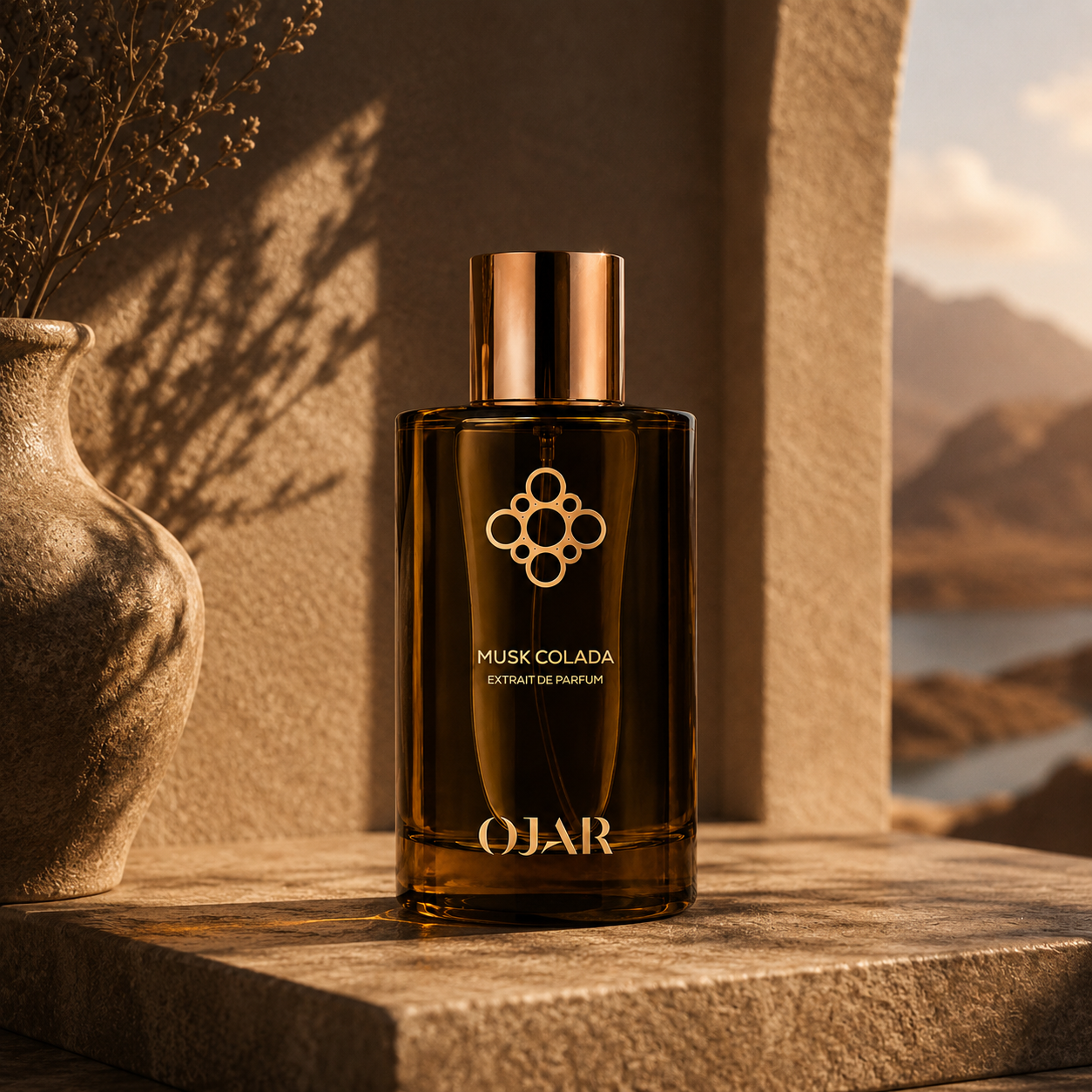 Musk Colada d'OJAR, extrait de parfum, flacon en mise en scène dans un décor minéral avec vase et végétation séchée.