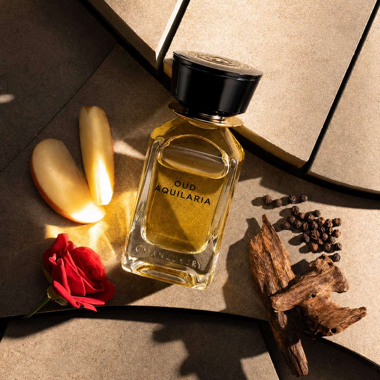 Oud Aquilaria by Oman Luxury flacon de parfum avec rose rouge, pomme, bois de oud et poivre noir sur fond minéral